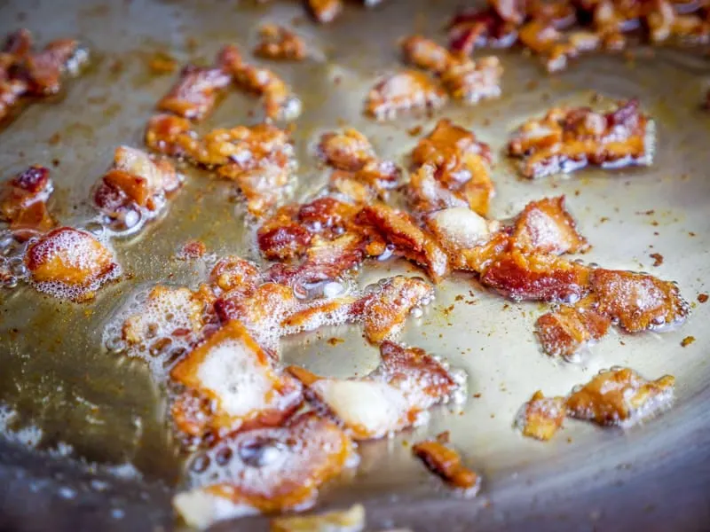 close up of chopped bacon cooking in a pan