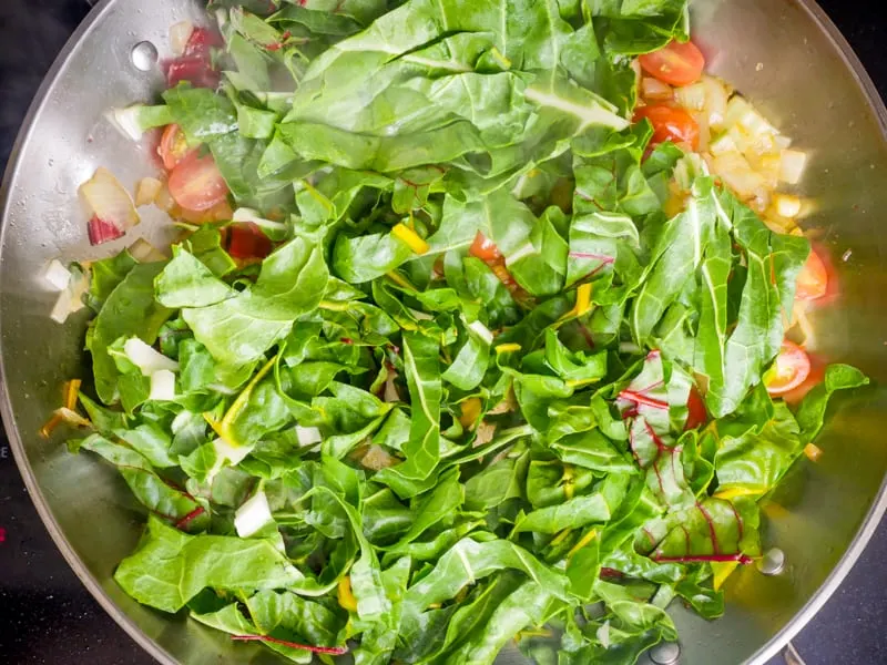Adding chopped chard leaves to the pan
