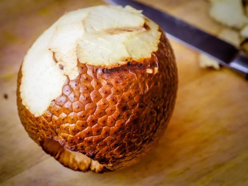 A peeled roasted breadfruit on a wooden cutting board