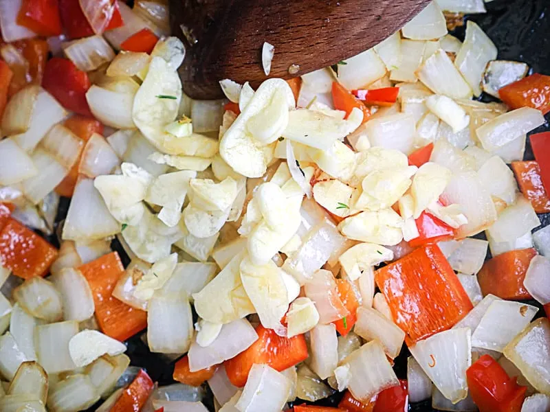 Sautéing onions, red bell pepper, and garlic in a skillet.