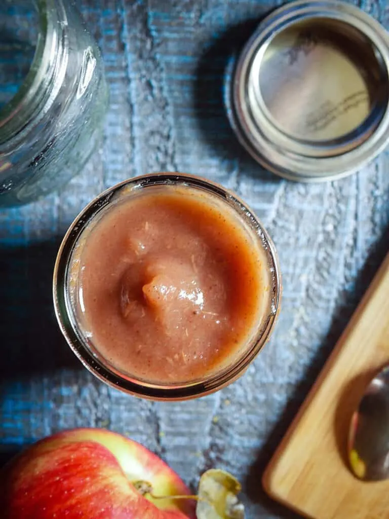 Overhead shot of an open jar of Instant Pot Apple butter on a blue wooden background.