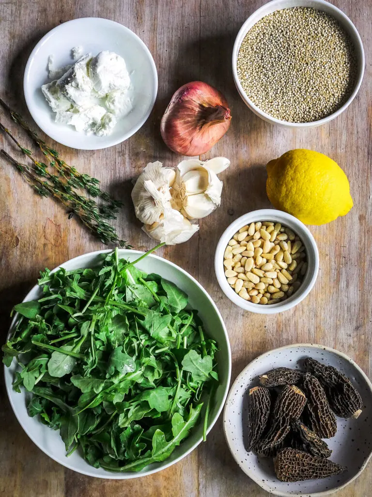 Overhead shot of Morel Mushroom and Quinoa Salad ingredients in white bowls on a wooden table.