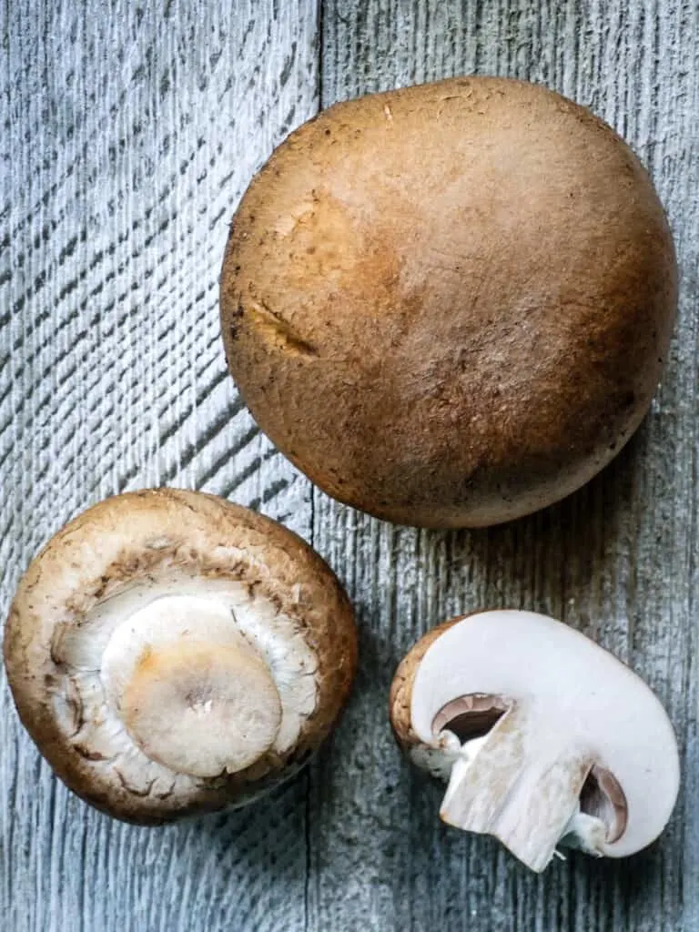 Image of three cremini mushrooms show various angles.