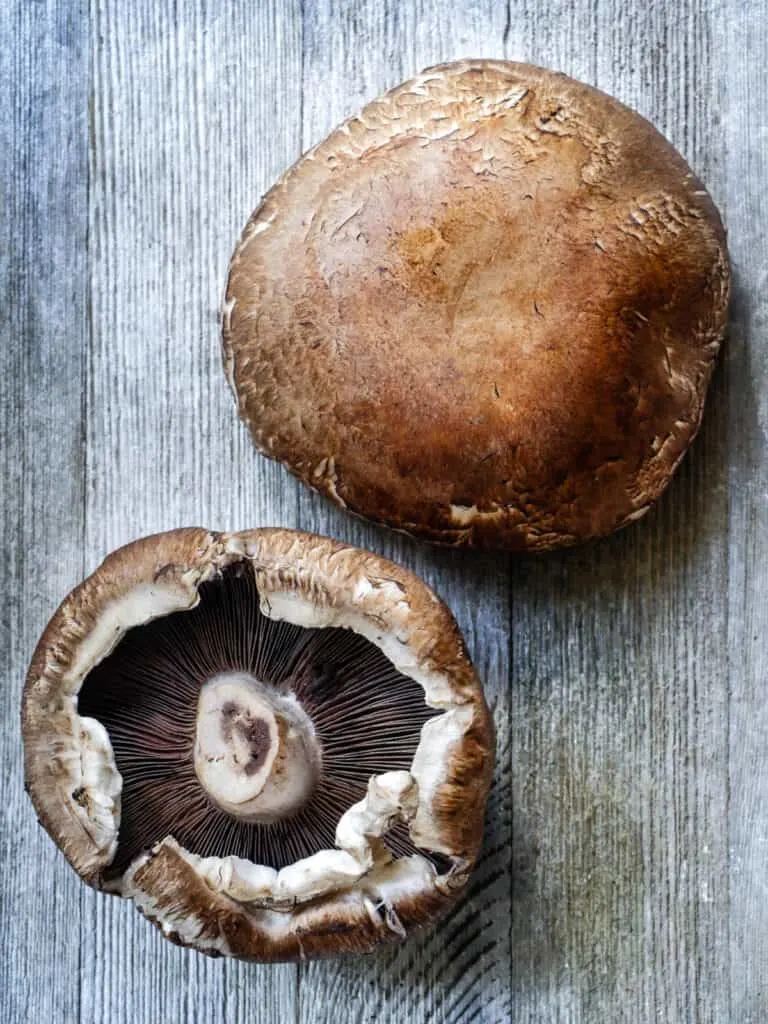 Image of two portobello mushrooms show the top side and underside of the cap.